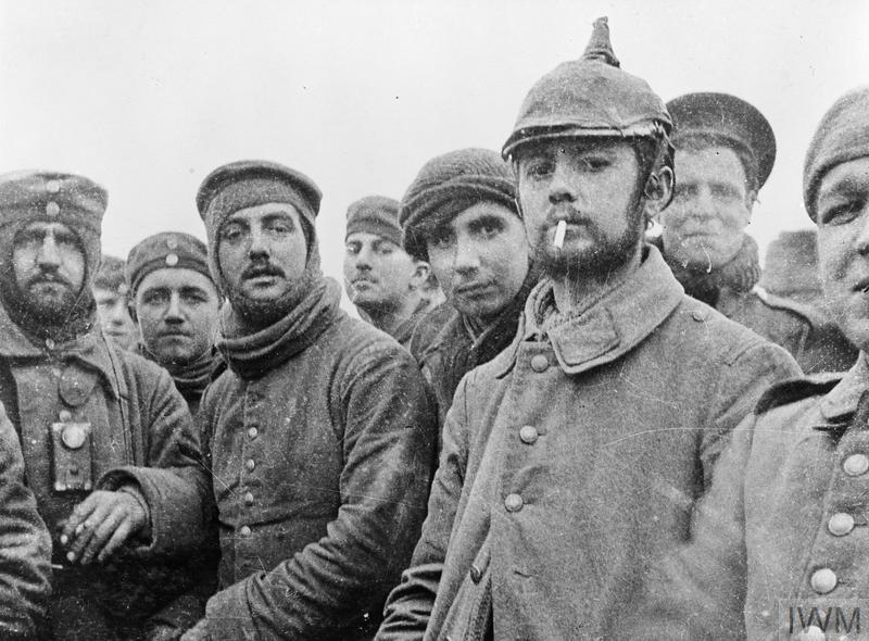 Britische und deutsche Soldaten in Wintermänteln stehen dicht beieinander.